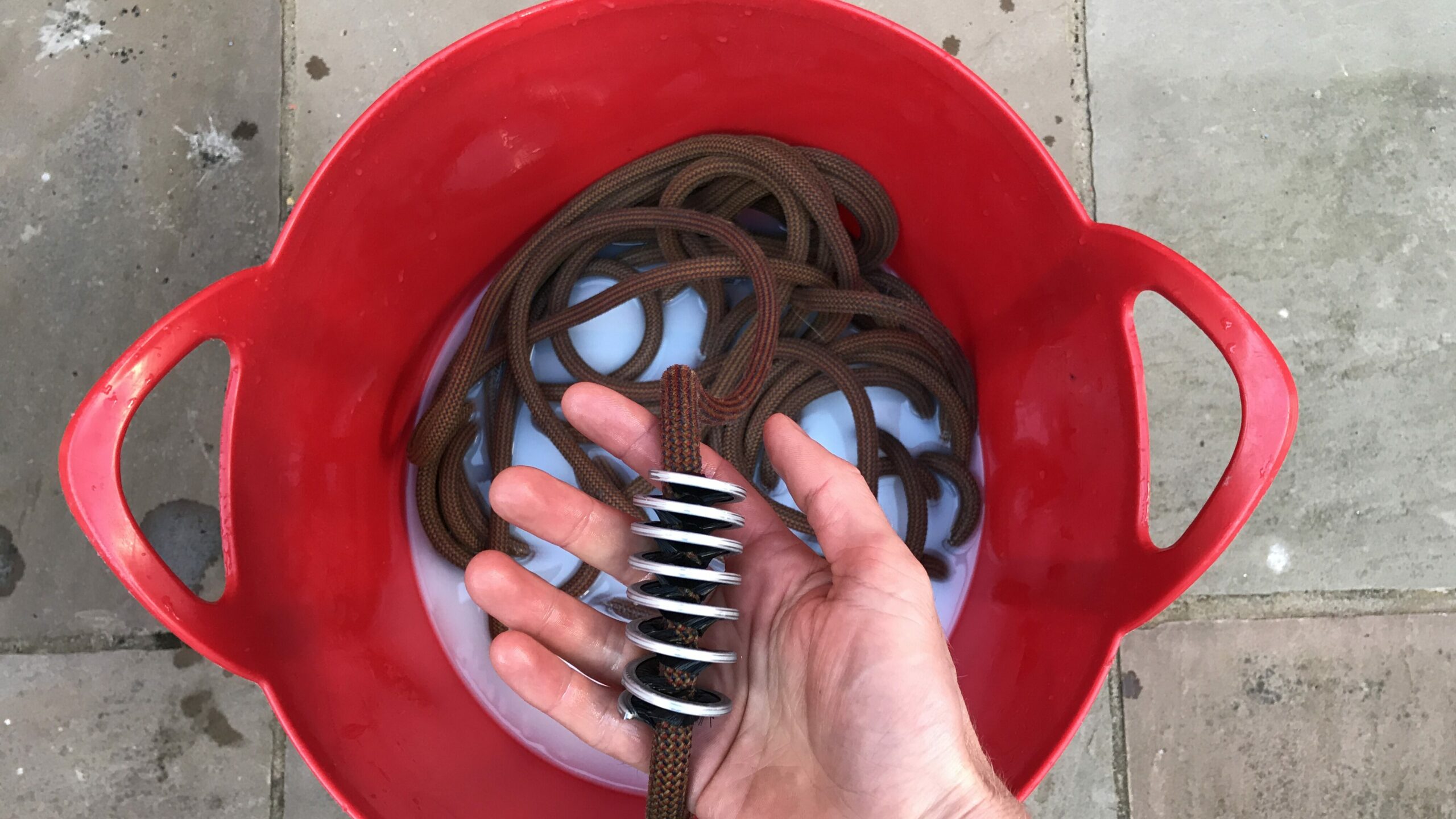 Using a rope brush to clean a dirty rock climbing rope.