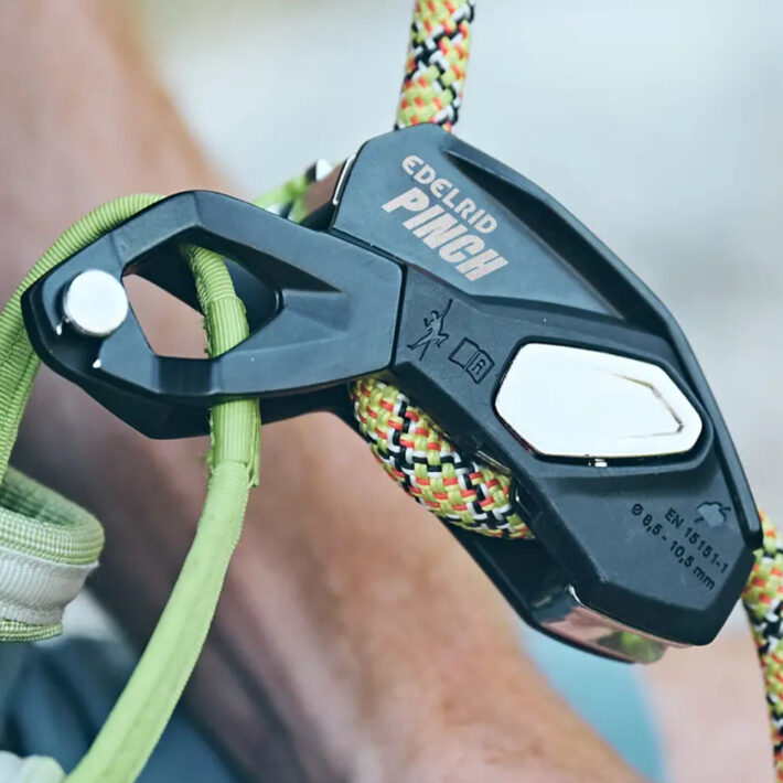 A photo of the Edelrid Pinch Assisted braking device, attached directly to a harnesses belay loop with a backup carabiner demonstrated.